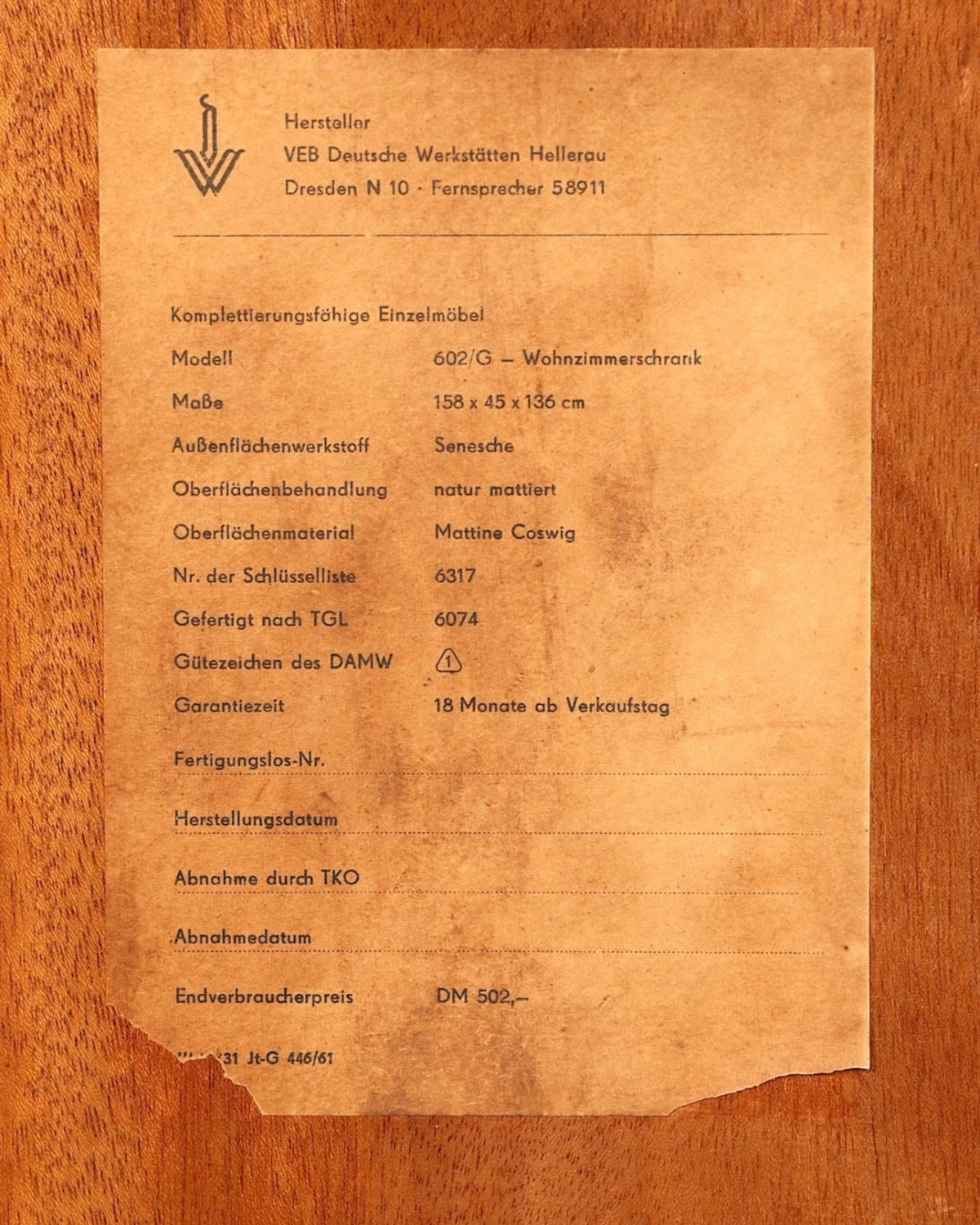 Originales Typenschild der Hauptstadt Möblerei Hellerau Vitrine Modell 602 von Franz Ehrlich auf Holzoberfläche